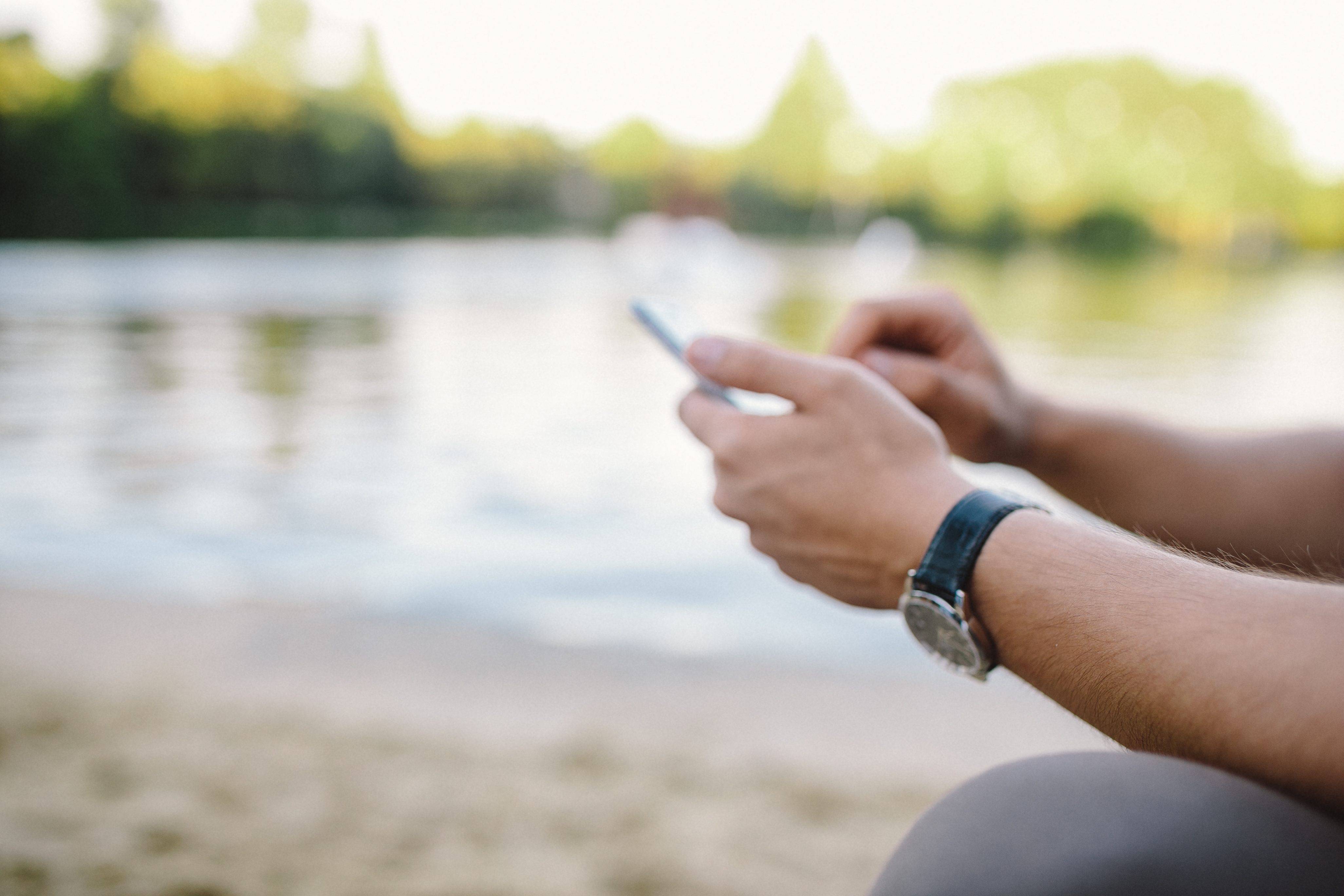 kaboompics_Young Man Using His Phone on beach